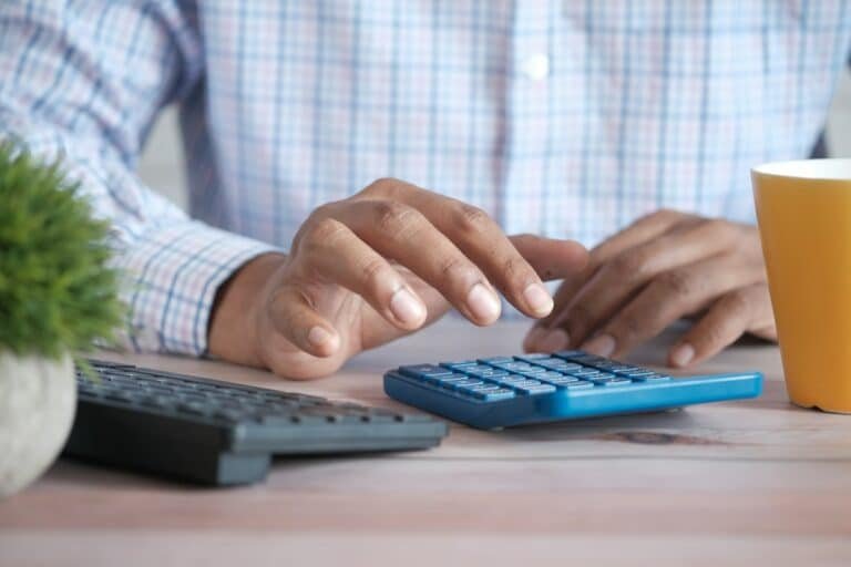 Manos con una calculadora revisando el saldo e intereses de un crédito