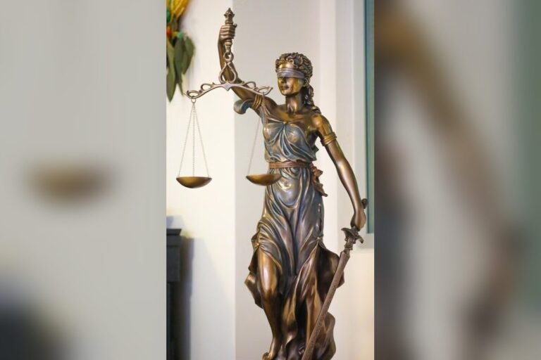 Estatua de bronce de la justicia con los ojos vendados, que sostiene una balanza en una mano y una espada en la otra.