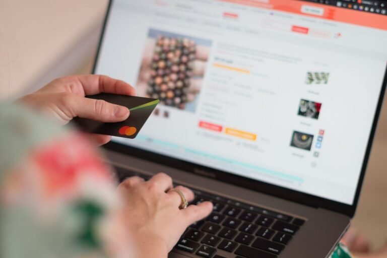 Persona con una tarjeta en la mano compra en una tienda virtual desde un computador portátil
