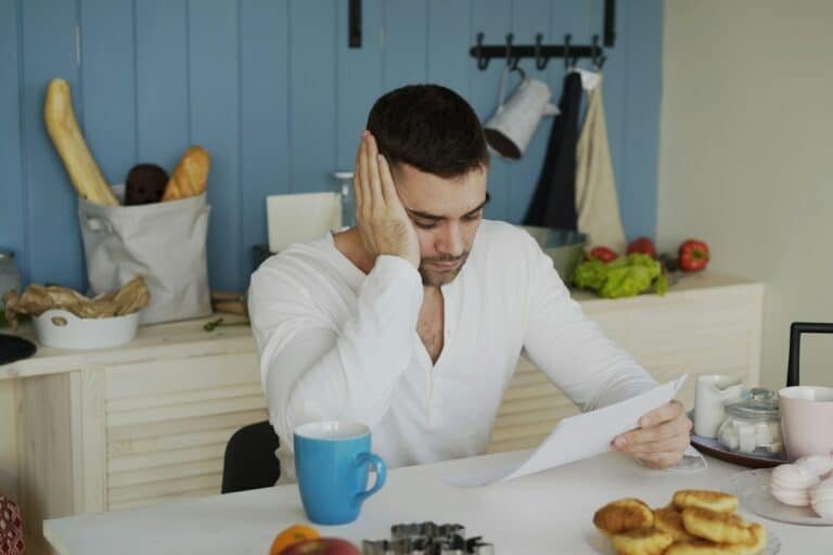 Hombre lee preocupado la carta de respuesta negativa del banco